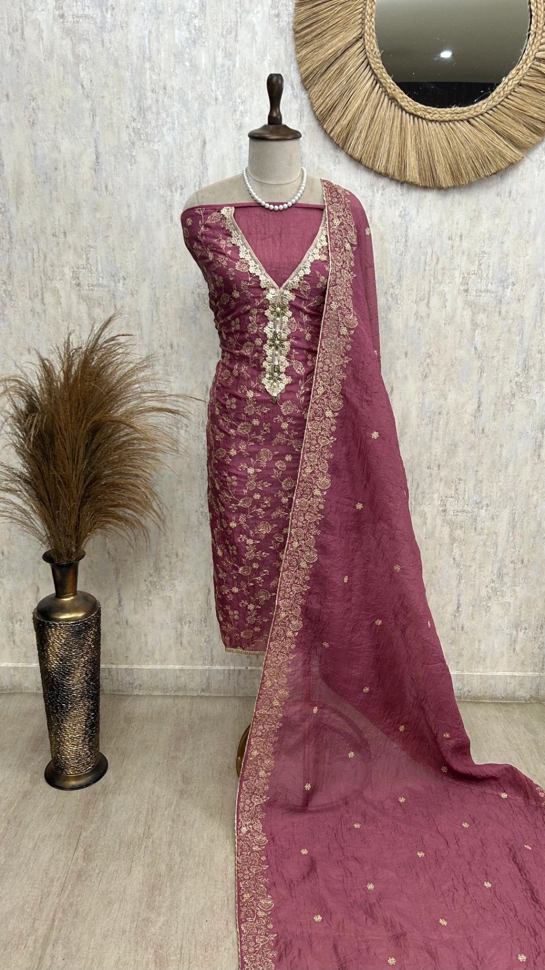 Mauve embroidered saree with a mannequin against a neutral wall.
